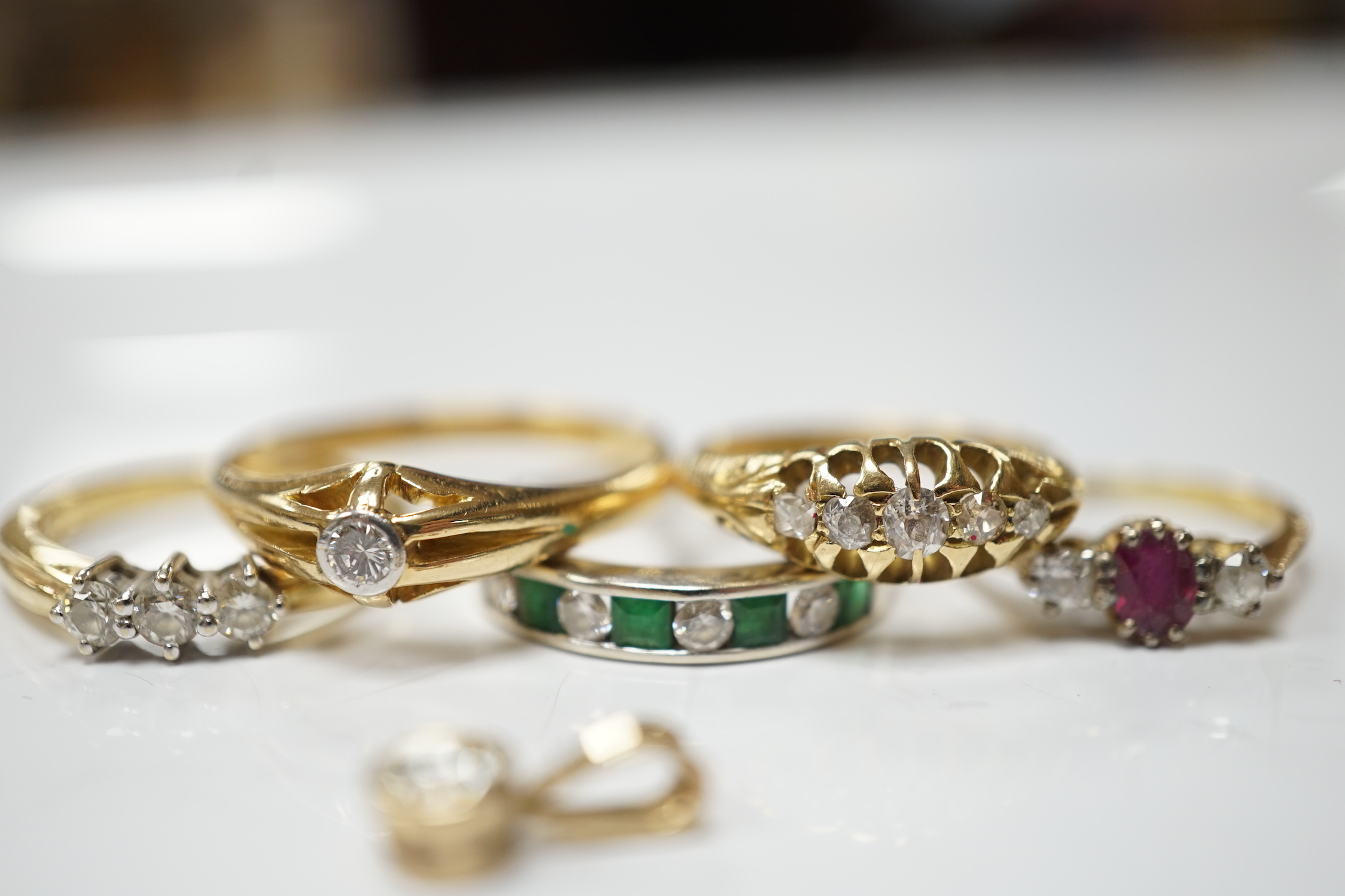 Four assorted early 20th century and later 18ct and gem set rings, including solitaire diamond and three stone diamond, gross 14.6 grams, together with a white metal and channel set emerald and diamond half hoop ring and